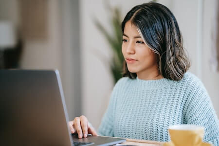 Female student using laptop near tea mug in room - employment reference letter