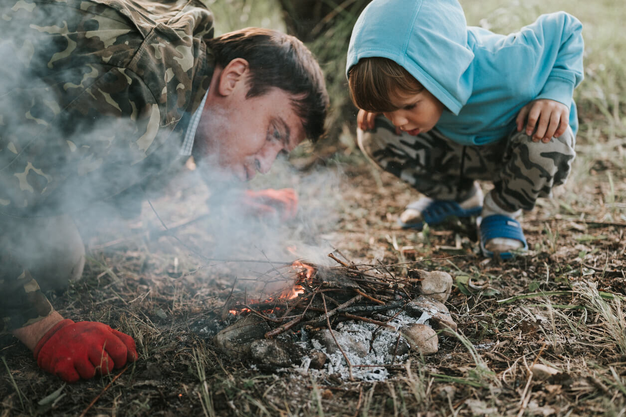 little happy five year old kid boy and his father blowing and kindles a campfire in the village or forest on nature outdoor on a summer evening. authentic countryside and children's rustic life Ultimate Father-Son Camping Trip
