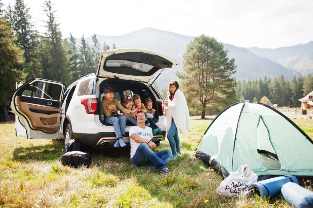 Large family of four kids. Children in trunk. Traveling by car in the mountains, atmosphere concept. American spirit.