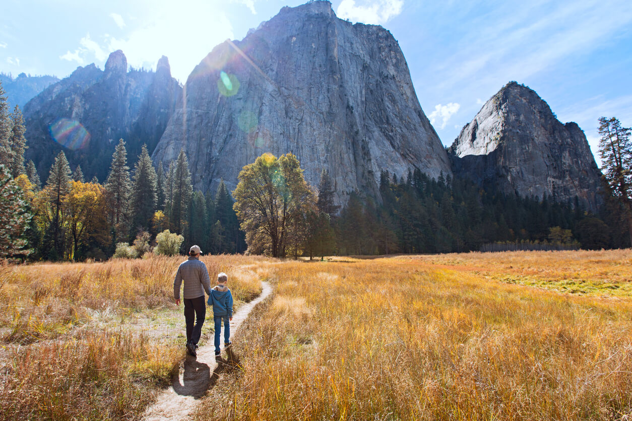 best hiking trails for kids dad and son at a nation park hiking outdoors outside nature hike back view of active family of two, father and son, enjoying valley and mountain view in yosemite national park, california, active family vacation concept
