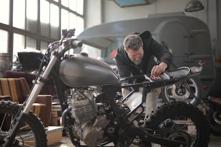 Man in Black Jacket Standing Near Black Motorcycle - is capital goods a good career path