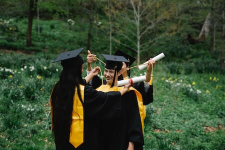 Group of Friends After Graduation Wearing Graduation Gowns, Mortarboards and Holding Diplomas - college job boards