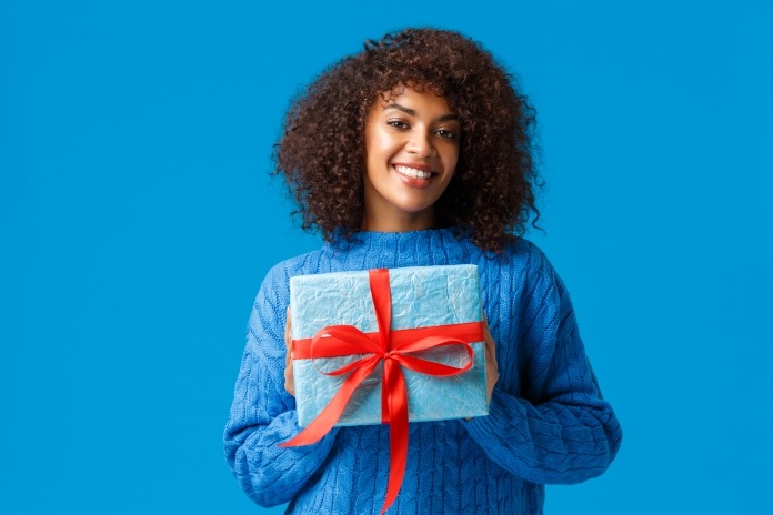 Holidays, winter season and christmas concept. Lovely cute african-american woman wrapped her present to give it boyfriend on valentines day, smiling cheerful, saying happy new year
