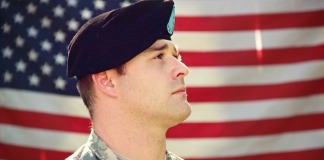 Man Wearing Combat Hat And Top Looking Up Near Flag Of America - hire military veterans