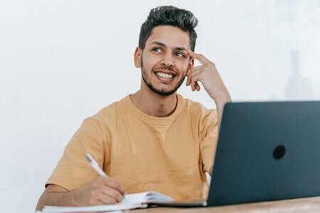 Man with computer and notebook smiling and looking off into space - fun jobs near me