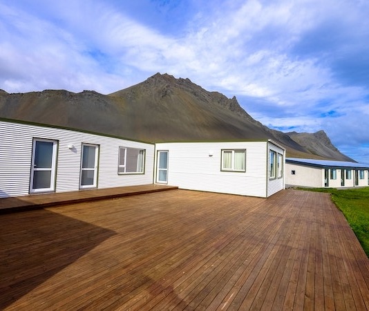Mountain Across Houses on Green Grass Field Under Clear Blue Sky - how to install a deck
