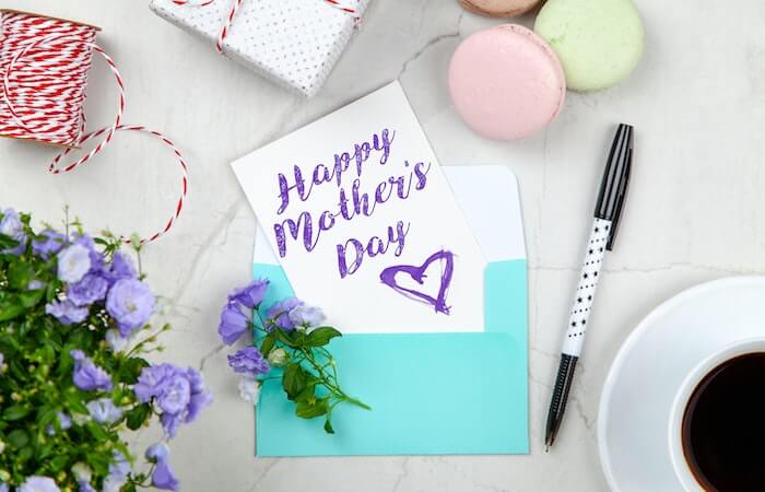 Happy Mothers Day Card Beside Pen, Macaroons, Flowers, and Box Near Coffee Cup With Saucer - mother's day flowers and chocolates