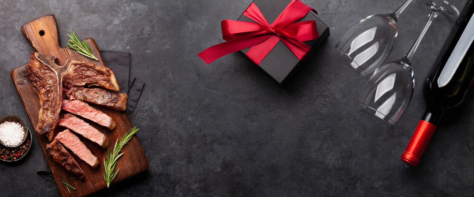 Valentines day or Christmas gift box with wine and grilled steak. Top view with space for your greetings. Flat lay gifts for the grill master